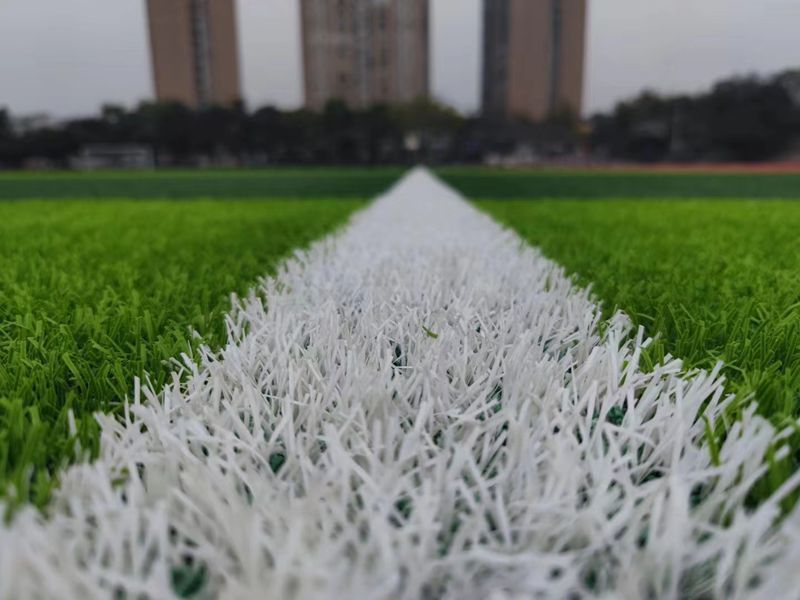 Why do human-made turf football fields need to be filled with rubber particles?